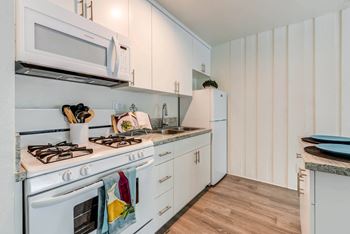 a kitchen with white cabinets and a stove and a microwave  at Rancho Los Feliz, Los Angeles, California